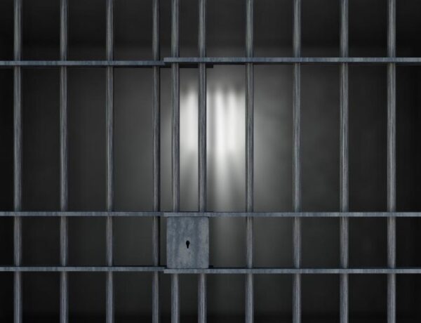 View into an empty prison cell through prison bars